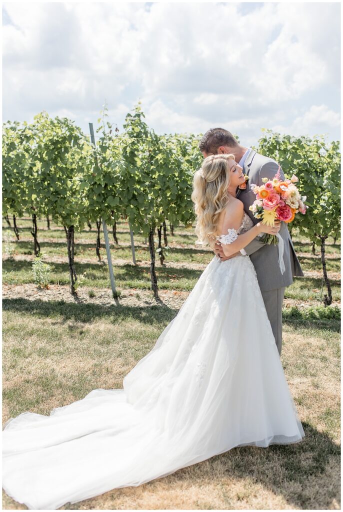 bride and groom hugging in vineyard on sunny summer day at folino estate