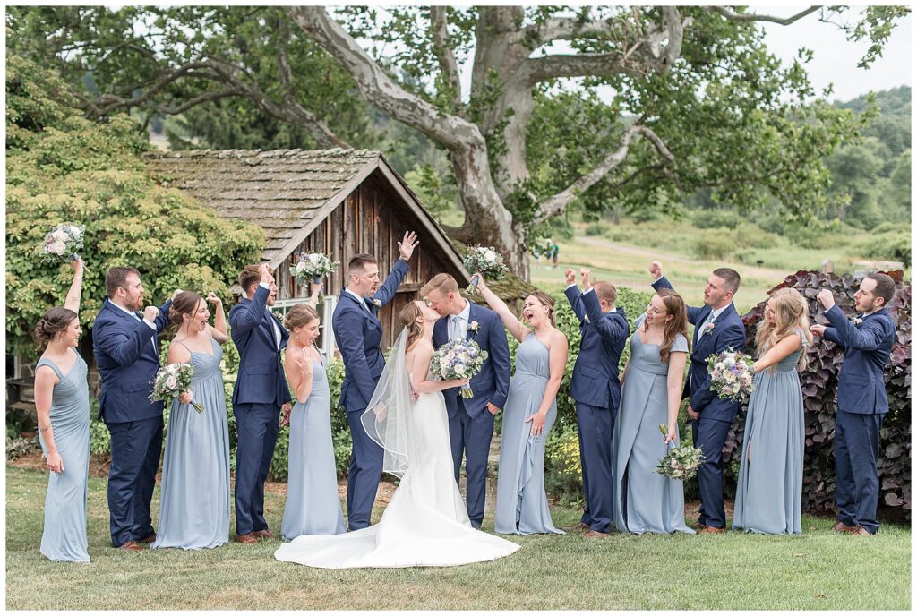 wedding party cheering as bride and groom share a kiss