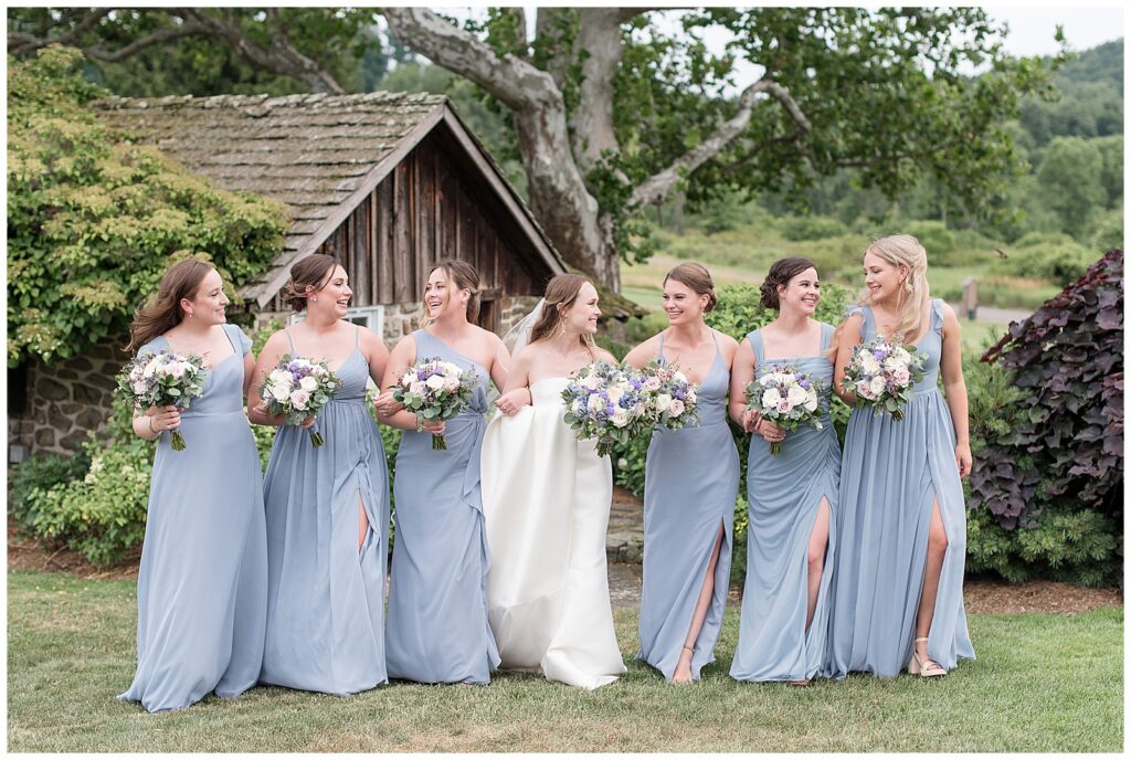 bridesmaids photo with girls all in light blue dresses holding bouquets walking arm in arm