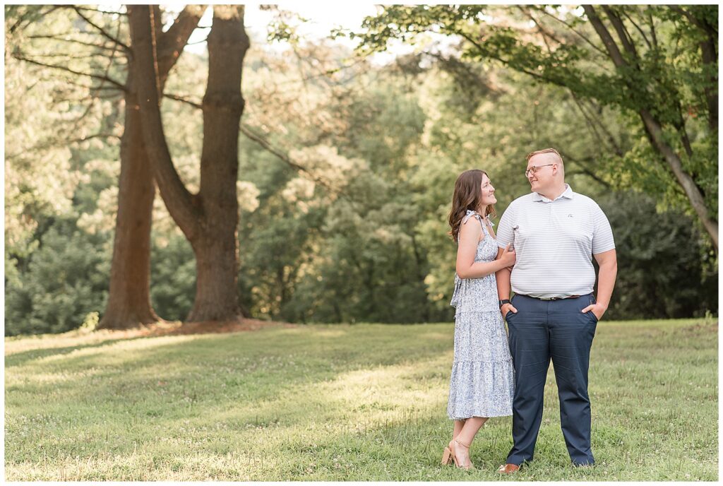 woman in light blue floral dress holding man's right arm as they smile at each other at lancaster county park