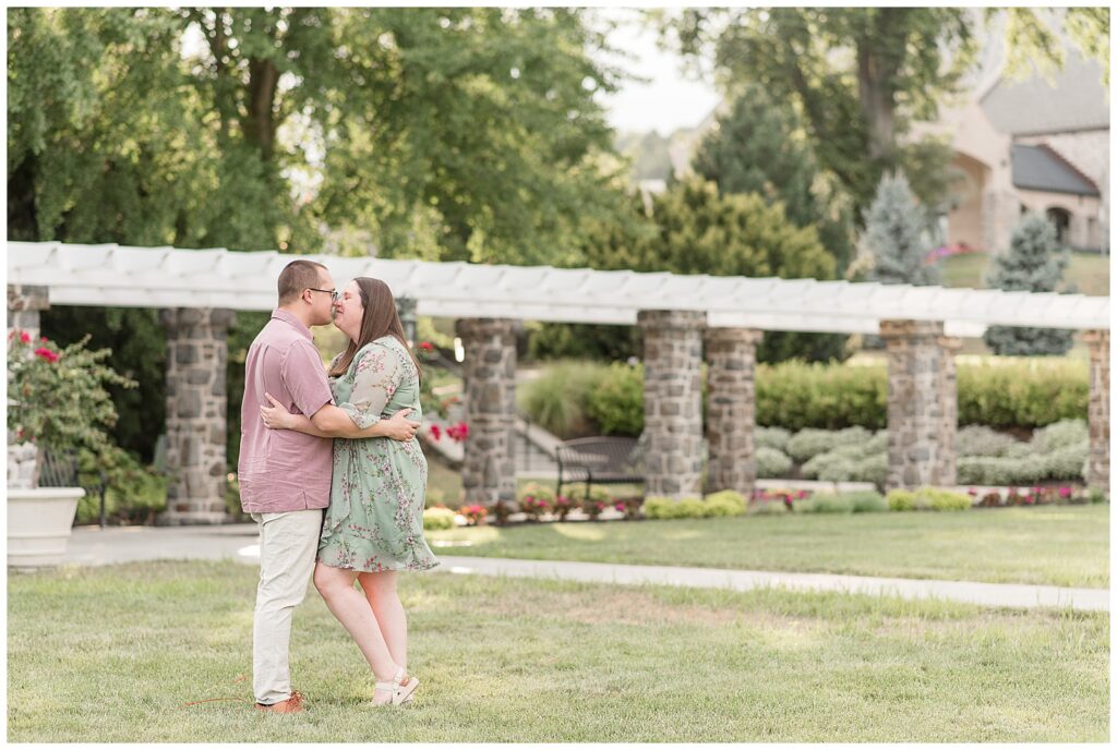 engaged couple kissing in lawn at sunset at masonic village in lancaster pennsylvania