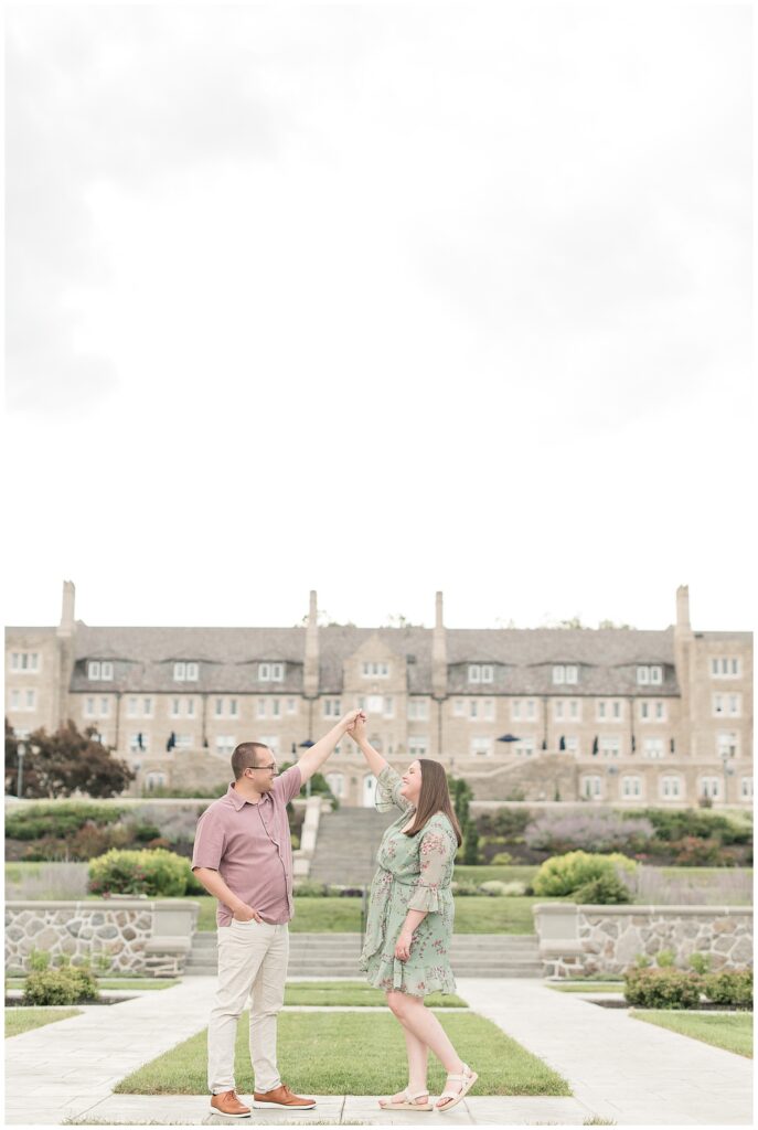 man twirling woman under his left arm in front of the grand entrance of the masonic village