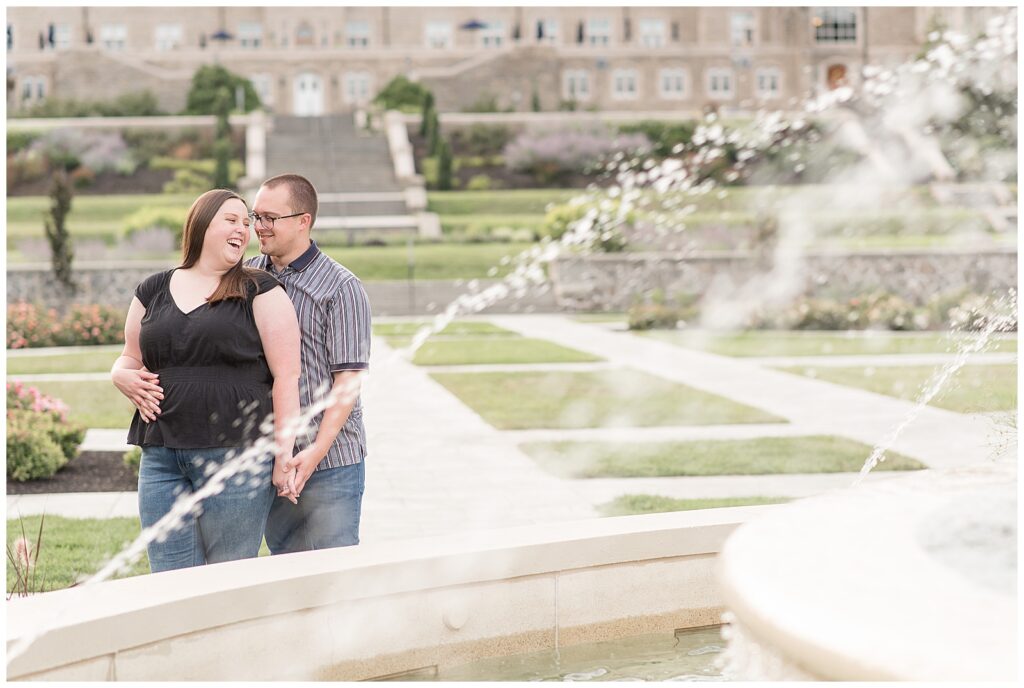 couple standing close and holding hands by water fountain at masonic village in etown 