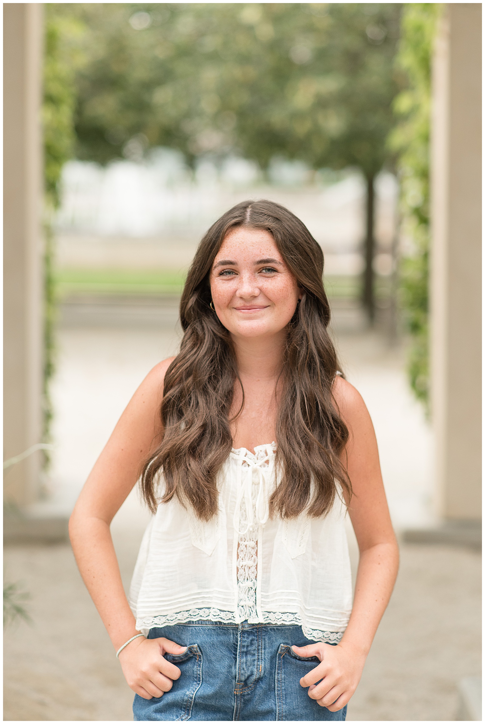 senior girl smiling at camera with hands in pockets at longwood gardens in kennett square