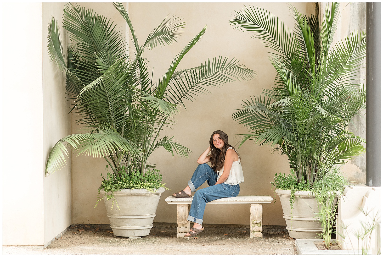 senior girl sitting on concrete bench with right foot on bench and leaning against bent knee in chester county pennsylvania