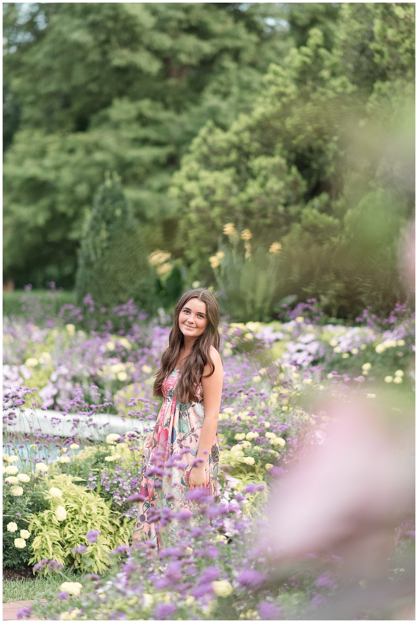 senior girl in floral dress amidst field of colorful wildflowers at longwood gardens in pennsylvania