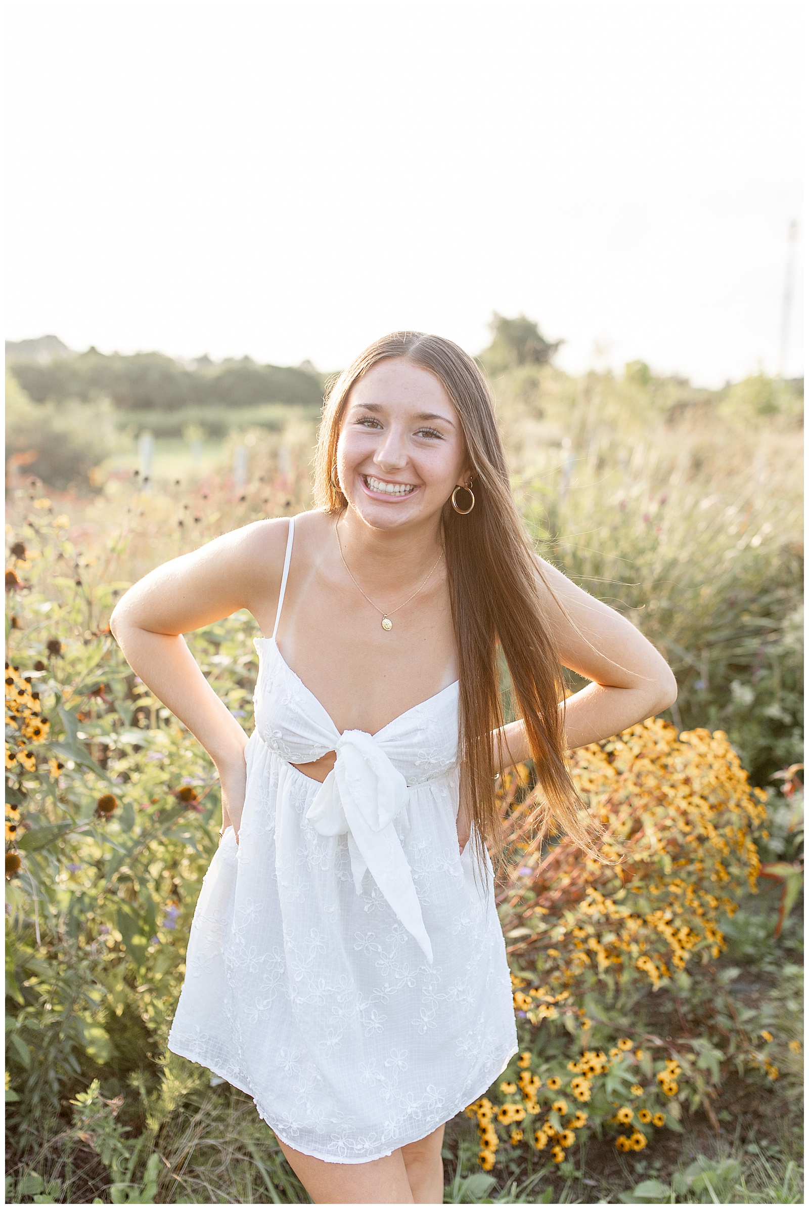 closeup photo of senior girl with hands on hips in wildflower field at sunset at park in lancaster county