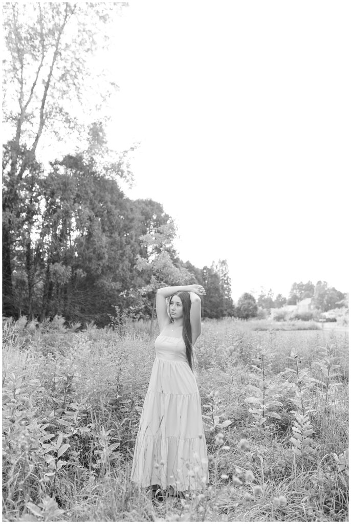 black and white photo of girl with arms resting on top of her head in wildflower field at overlook park