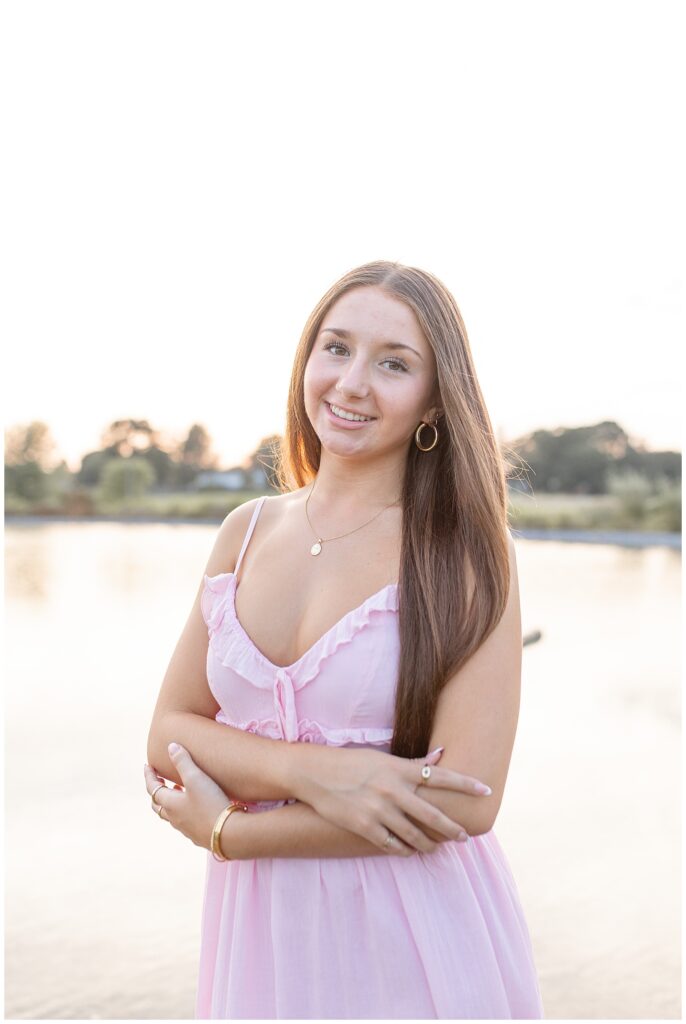 senior girl in light pink dress with arms folded in front of her by pond at park in manheim township