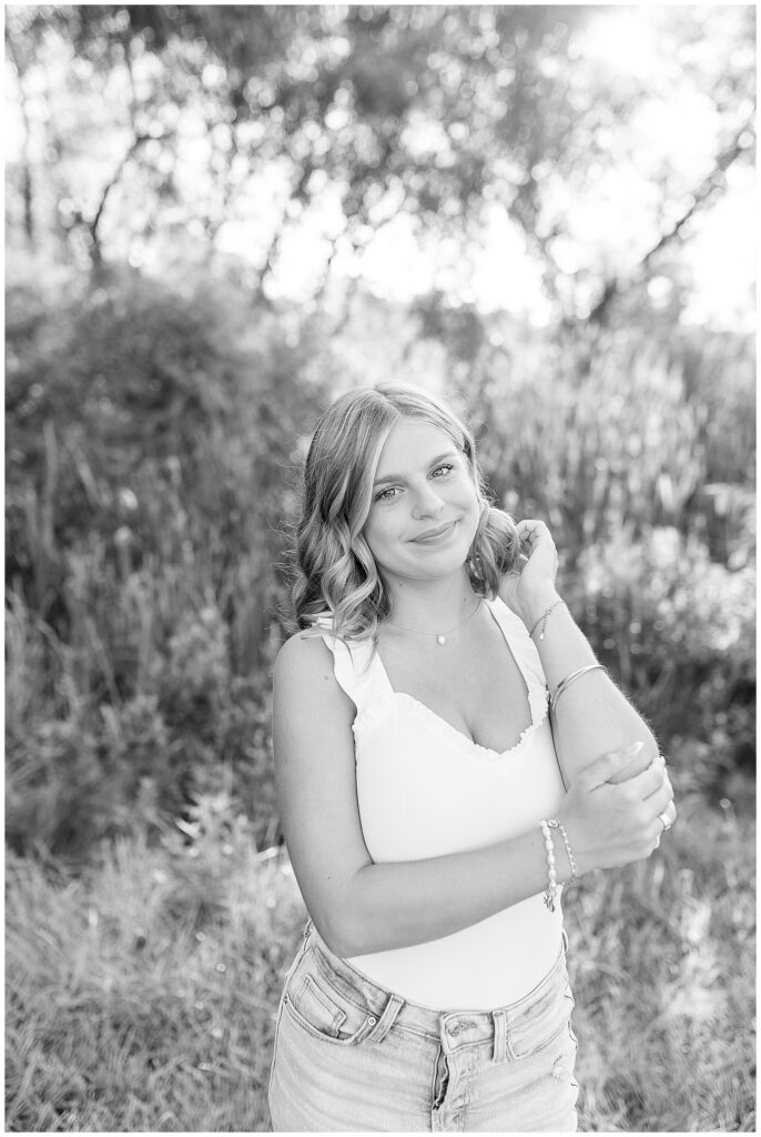 black and white photo of senior girl tucking her hair behind her left ear at overlook park in lancaster pa