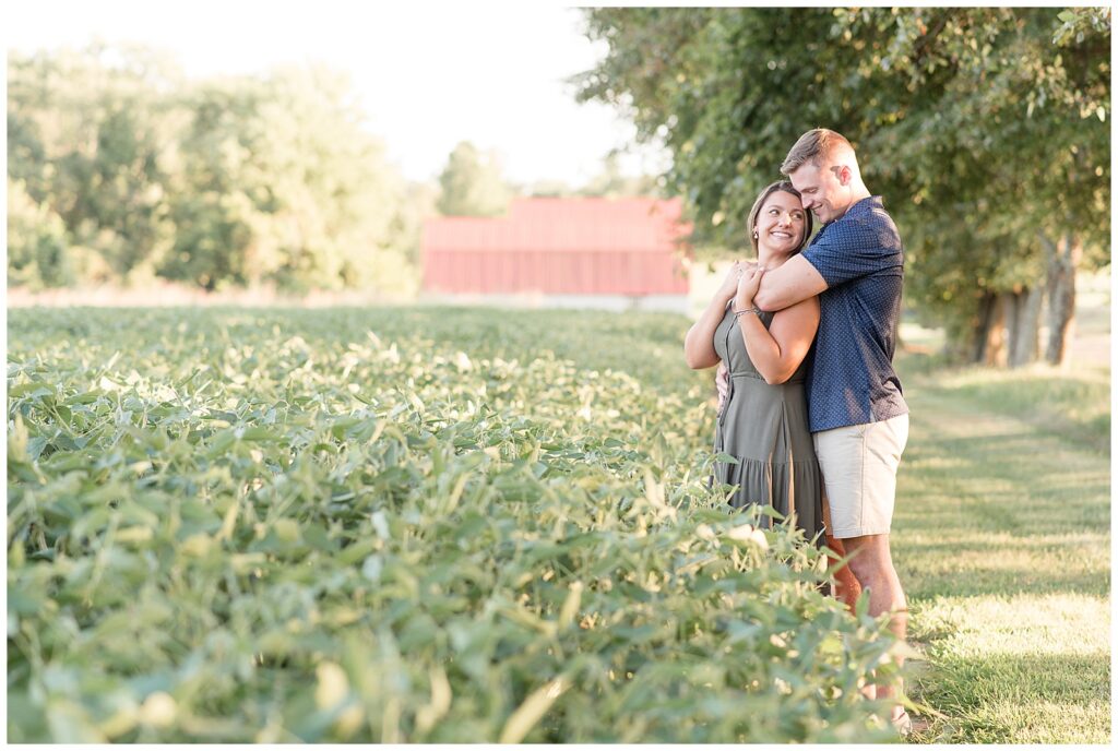 guy standing behind girl as they hug by field at family farm in chesapeake city