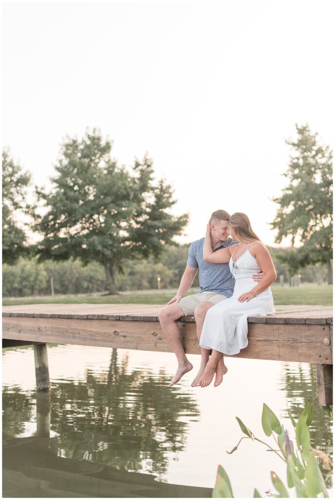 couple sitting on bridge and almost kissing at sunset in maryland