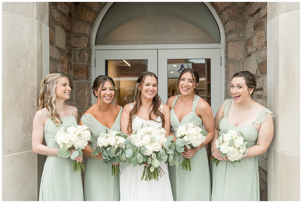 bride surrounded by her four bridesmaids in sage green gowns all holding bouquets in flourtown pennsylvania