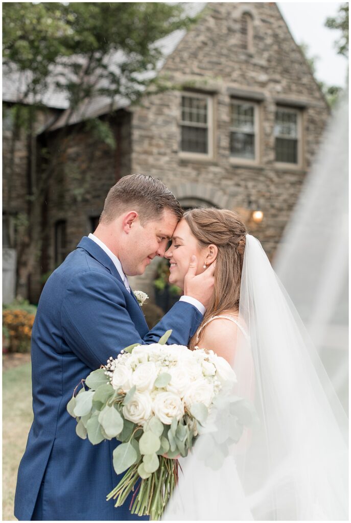 couple almost kissing with bride's veil surrounding them at flourtown country club