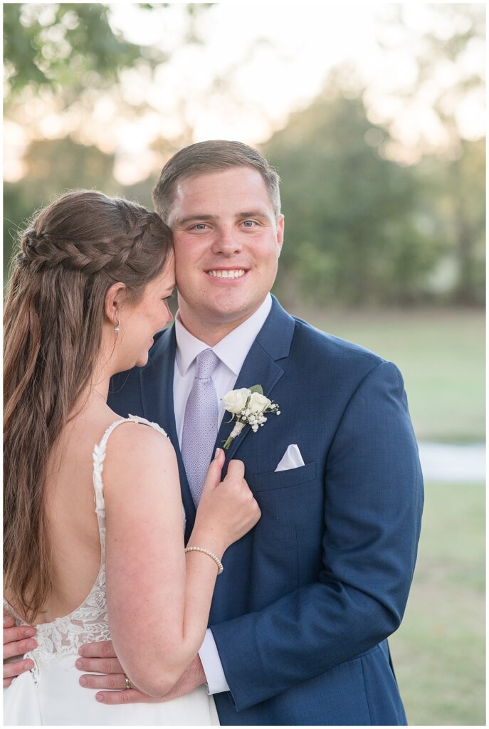 bride hugging her groom as groom looks and smiles at camera on golf course in pennsylvania