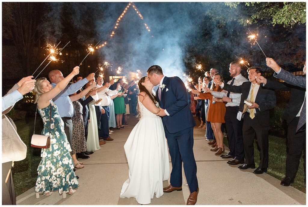 couple stopping to kiss during sparkler send-off at the end of their reception at flourtown country club in pennsylvania