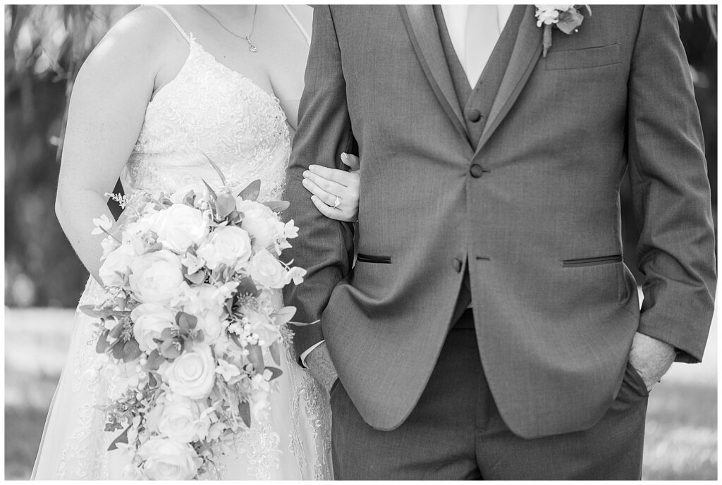 close-up black and white photo of bride holding groom's right arm as she holds her bouquet in new jersey