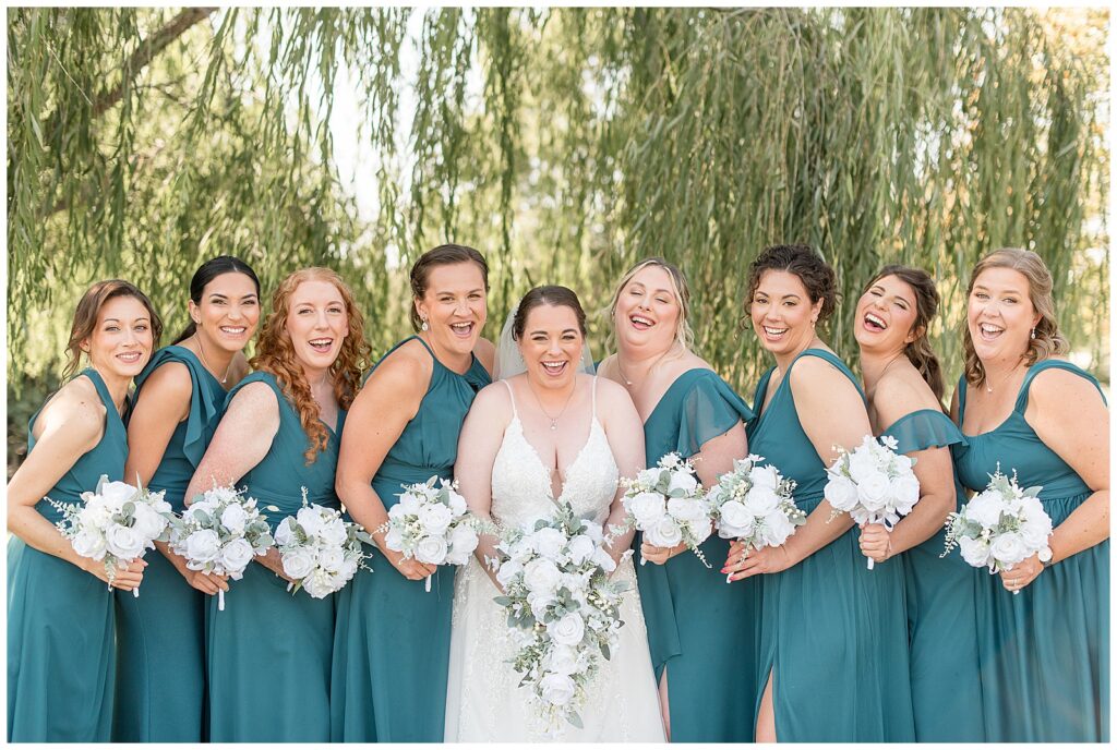 bride with her six bridesmaids wearing turquoise gowns and holding bouquets by willow tree in new jersey