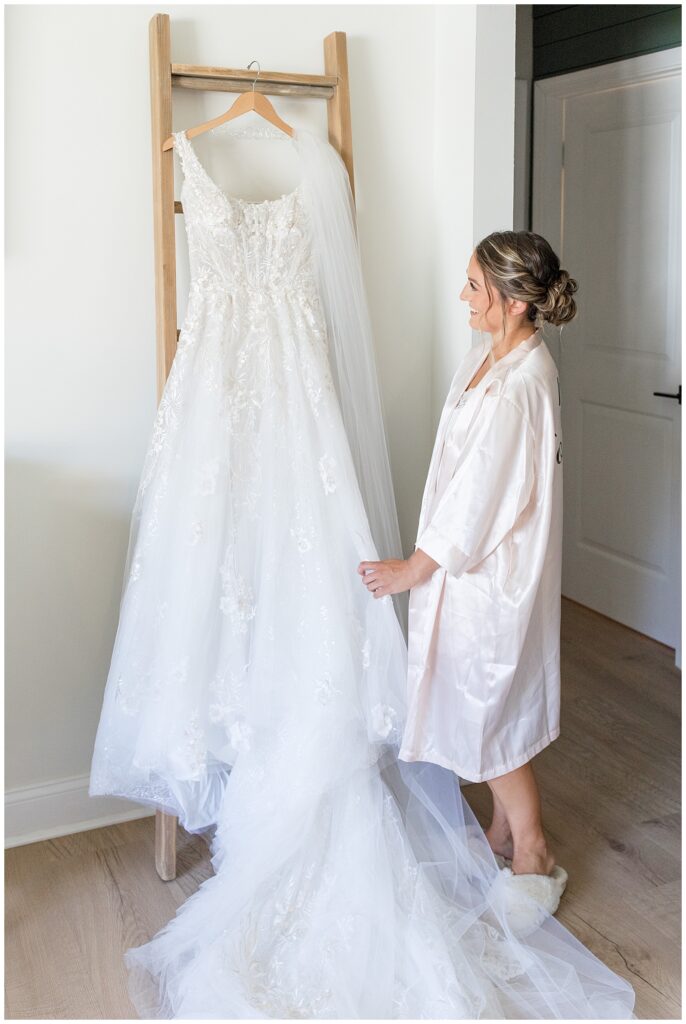 bride holding the edge of her white wedding gown that's hanging on the rung of a ladder in pennsylvania