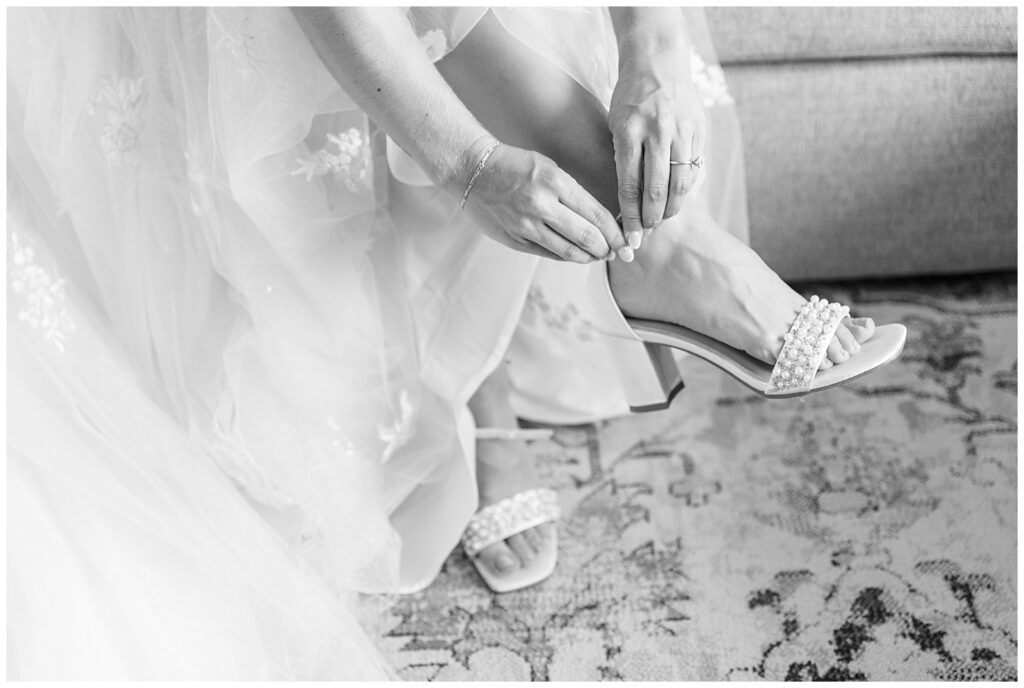 black and white closeup photo of bride doing the strap on her sandal at family farm in pennsylvania