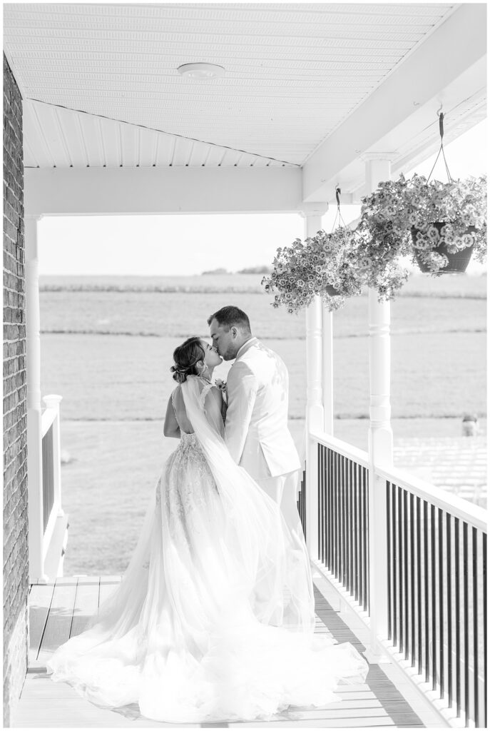 couple sharing a kiss on front porch of family farm before wedding ceremony in pennsylvania