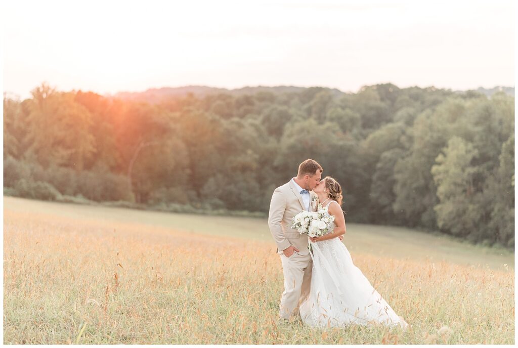 couple kissing in field with sunset behind them on fall evening at bride's family farm