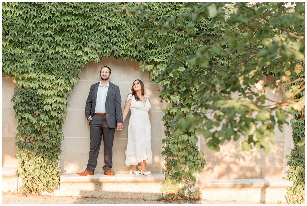 couple standing on concrete bench by ivy-covered wall at sunset at longwood gardens