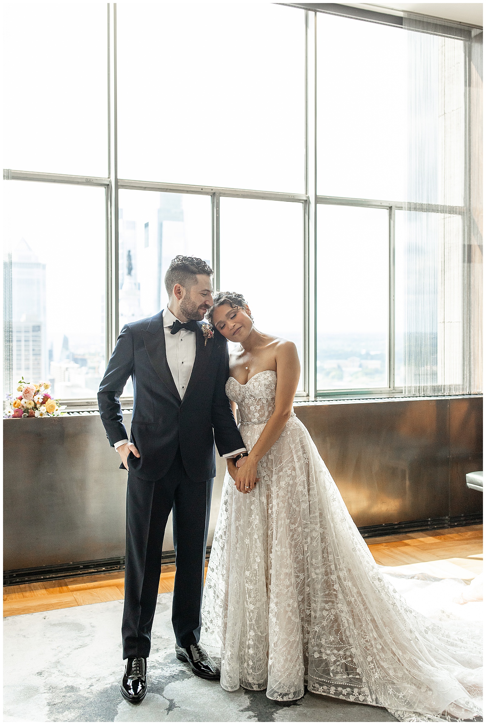 bride resting her right temple on groom's left shoulder as he looks at her in industrial-looking room in philly