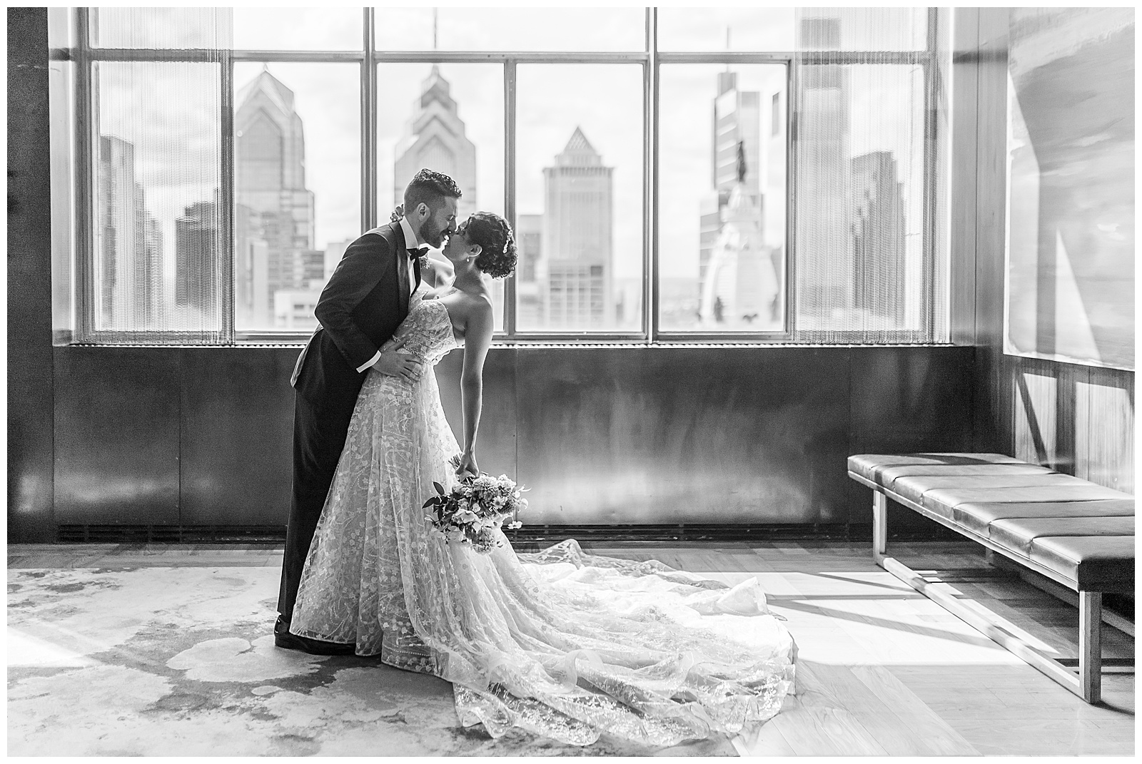 black and white photo of couple kissing with philadelphia skyline in background