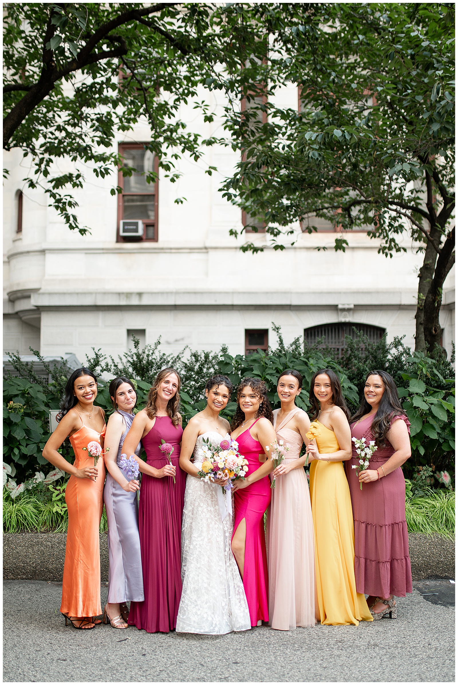 bride with her seven bridesmaids in vibrant colors of the rainbow gowns on street in philadelphia