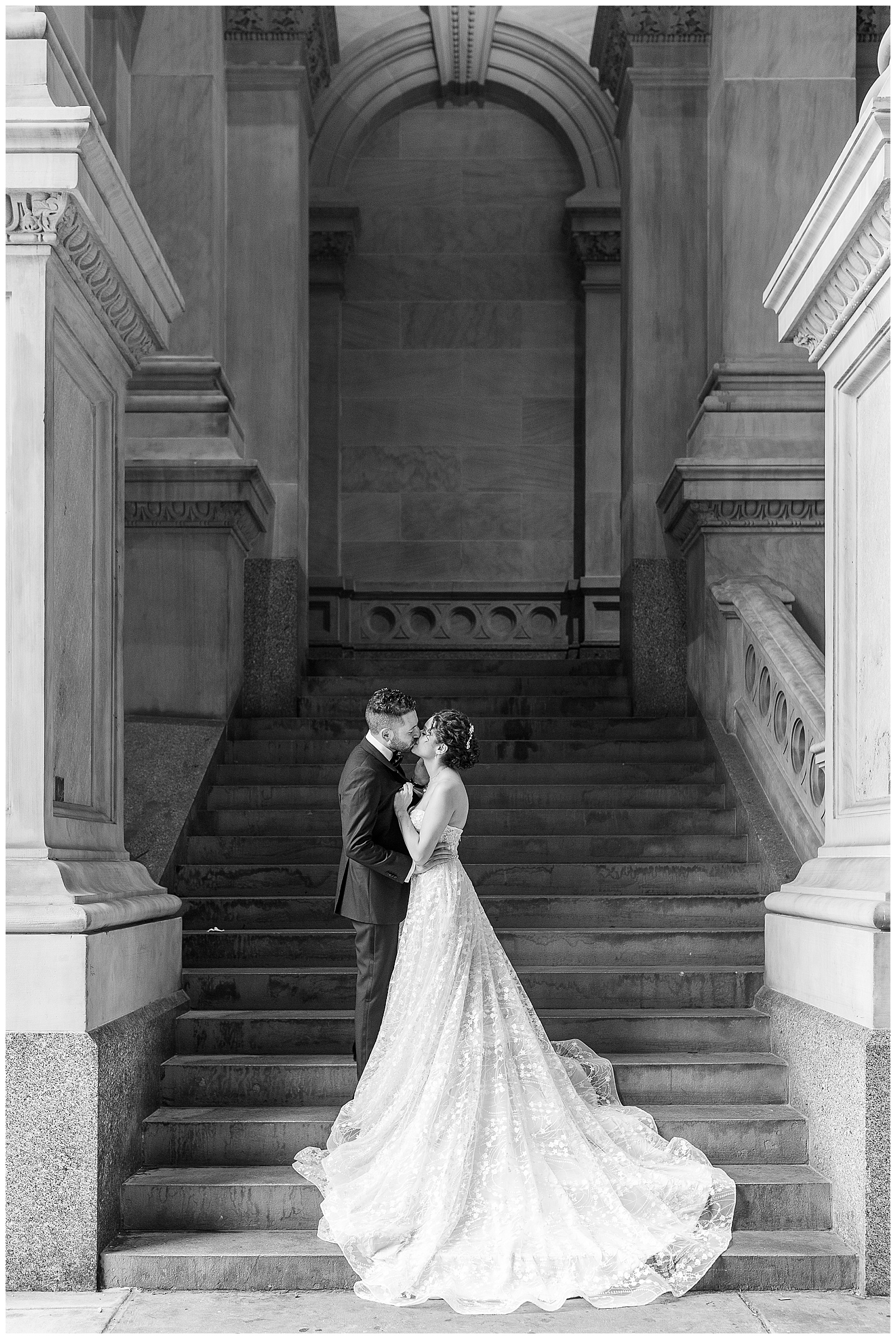 black and white photo of couple kissing at the bottom of steps of historical building in downtown philadelphia