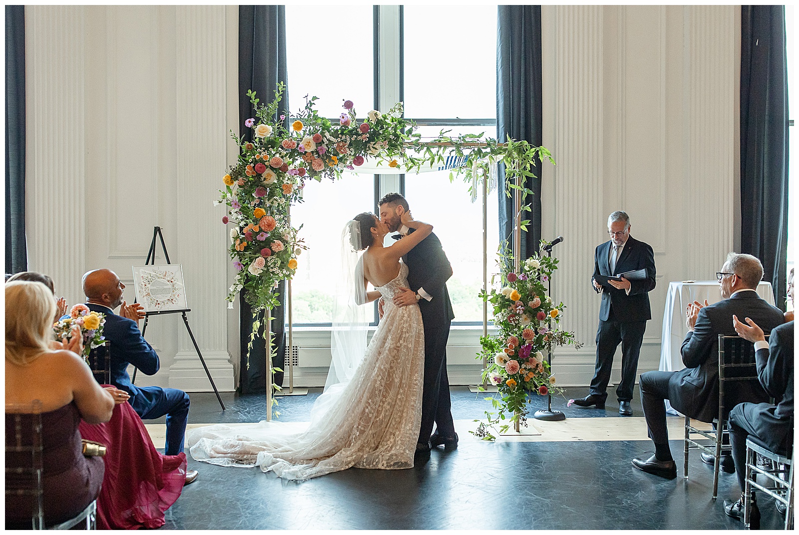 couple kissing during their first dance by floral archway at cescaphe in philadelphia