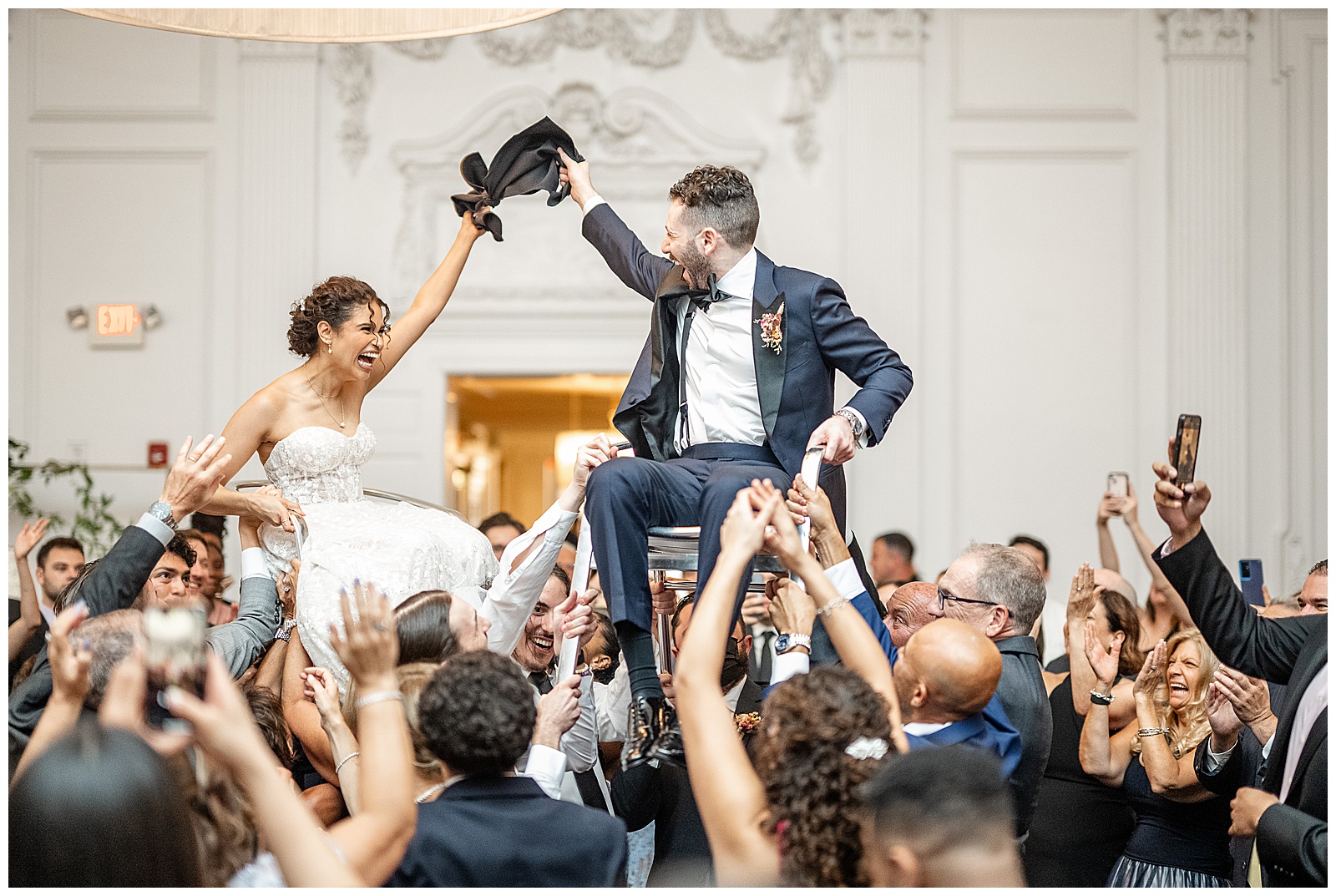 couple sitting on chairs being raised up above the crowd during reception at cescaphe