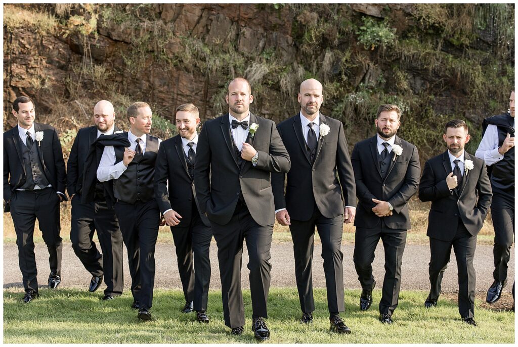 groom with his eight groomsmen all walking towards the camera on sunny fall day in gettysburg pennsylvania