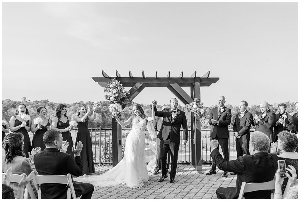 bride and groom celebrating with their arms raised as they hold hands leaving their outdoor wedding reception at the links at gettysburg