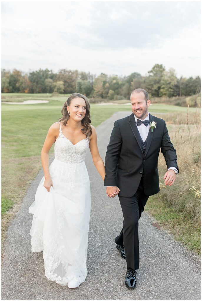 couple holding hands as they walk along golf cart path at the links at gettysburg at sunset in pennsylvania