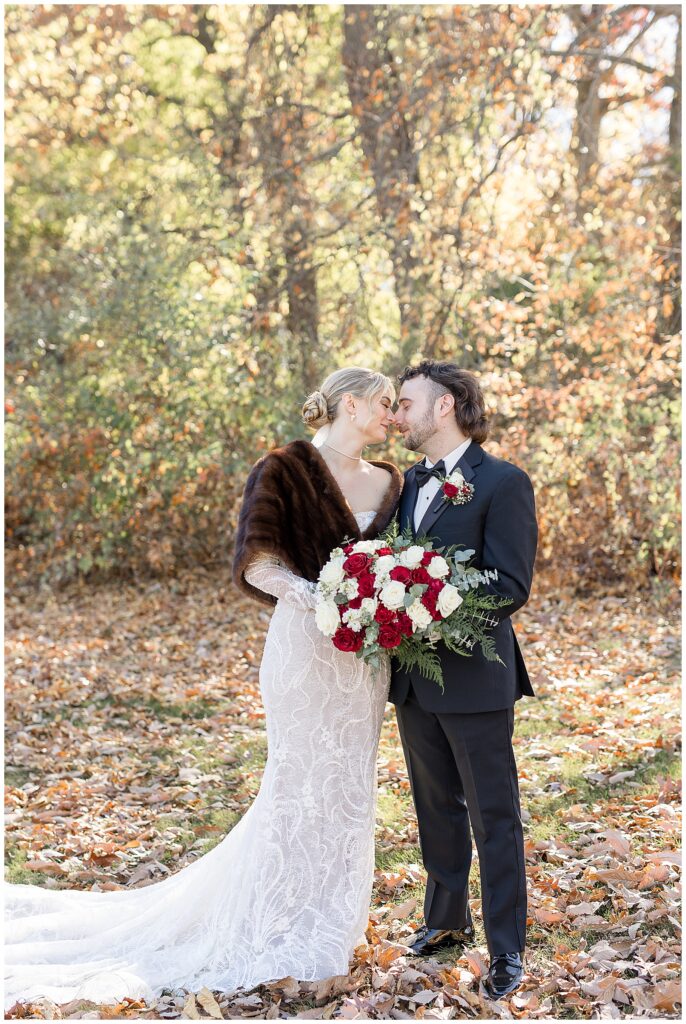 bride and groom touching noses on fall day with colorful trees behind them in york county pennsylvania