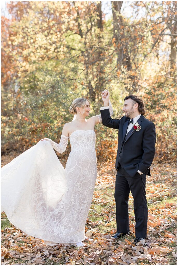 groom raising bride's left hand as bride holds up her white dress train with her right hand in york pa