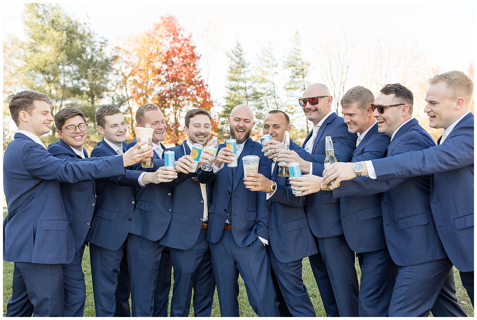 groom and groomsmen all huddled together with cups in hand as the celebrate before wedding at the barn at silverstone