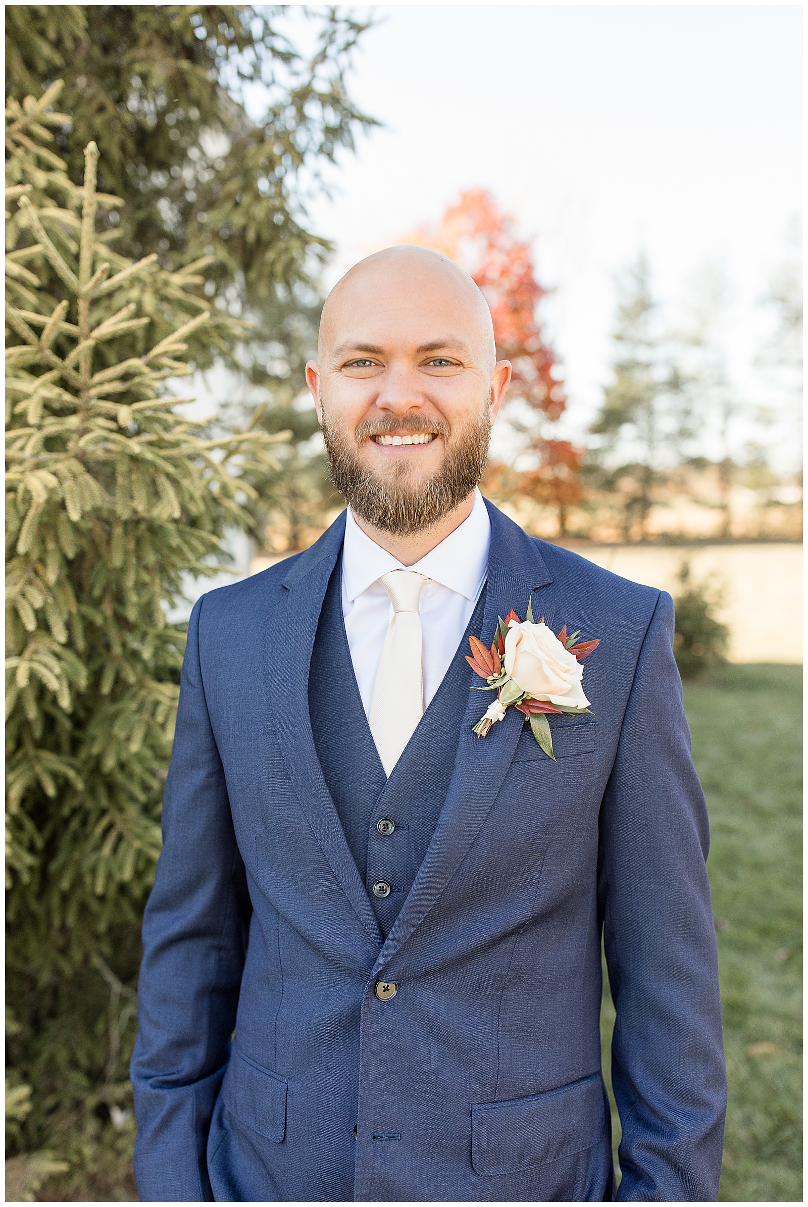 groom in navy blue suit and vest smiling at camera on sunny fall afternoon at the barn at silverstone