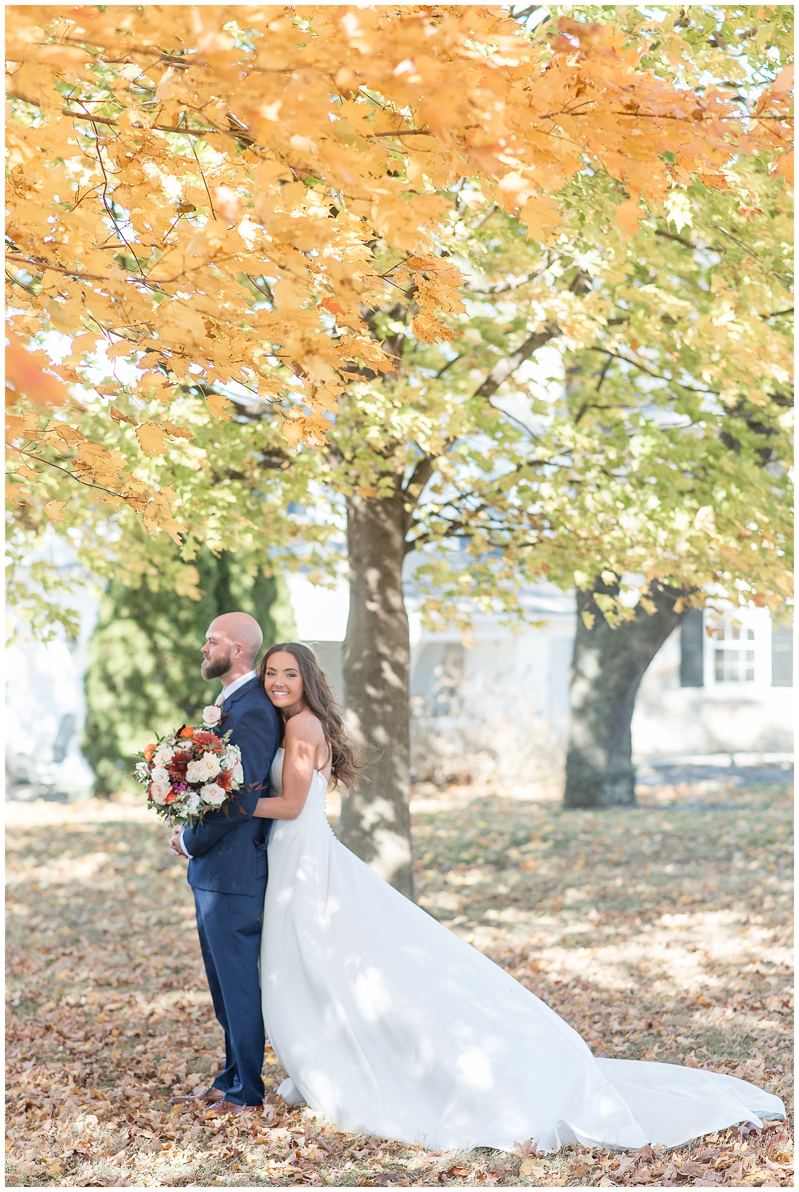 bride hugging her groom from behind with her long dress train behind her on fall day in lancaster pa