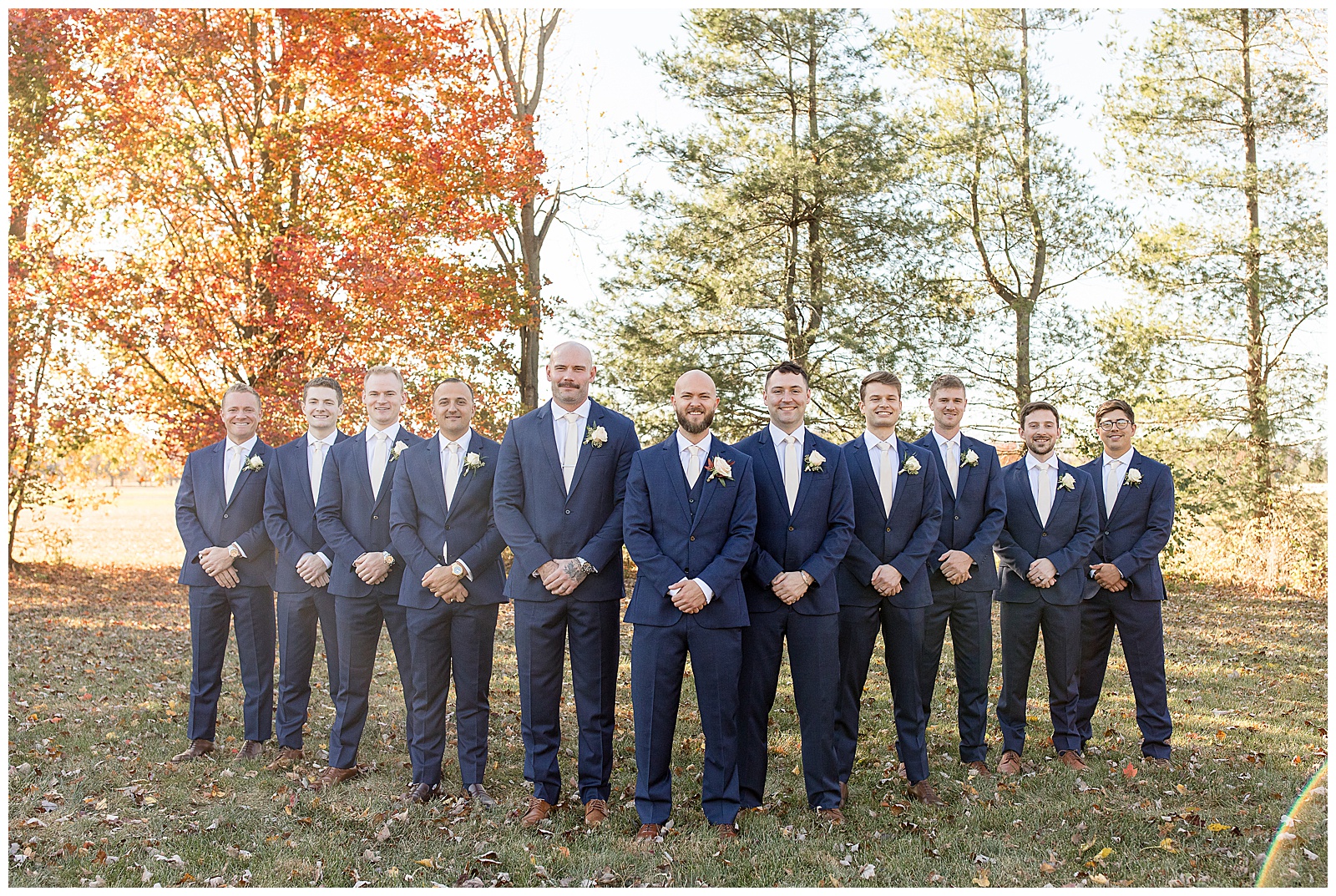 groom with his groomsmen all wearing navy blue suits and standing in a V shape at the barn at silverstone