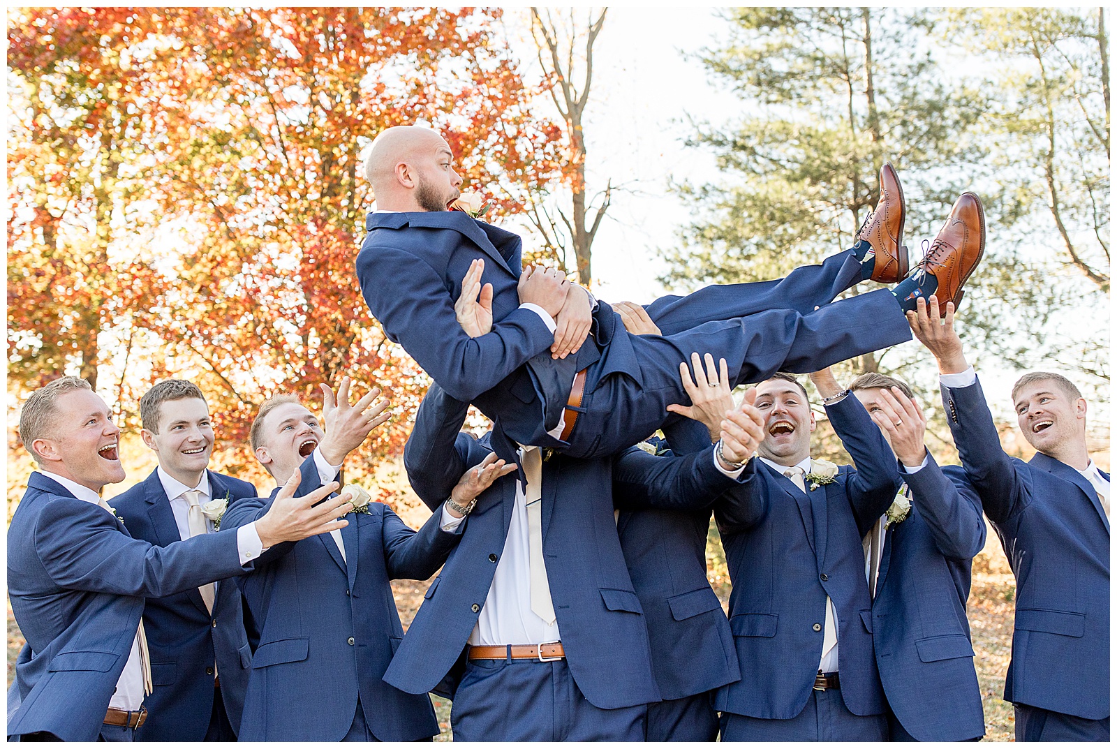 groomsmen lifting the groom overhead as they cheer on fall day at the barn at silverstone