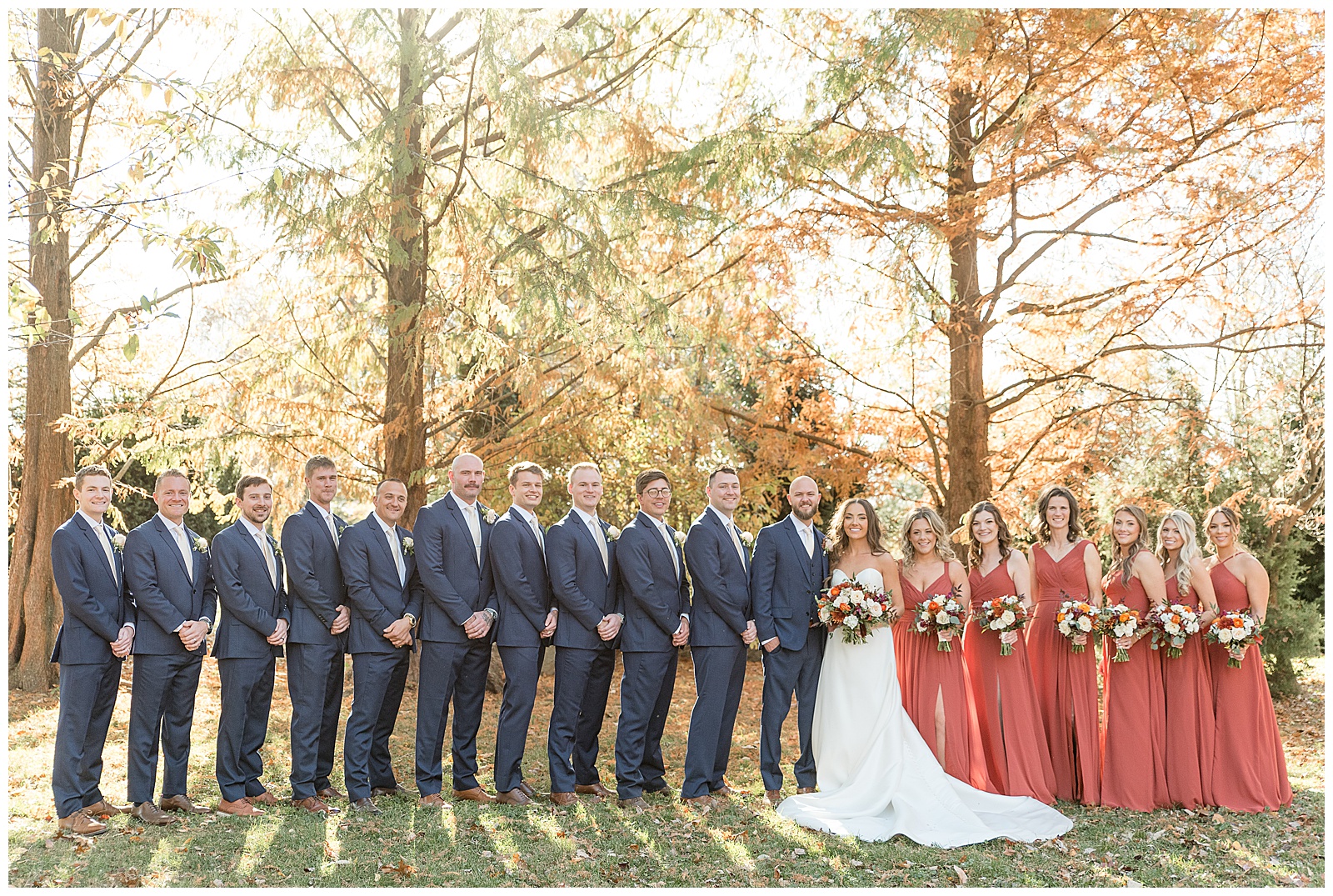 bride and groom with their full bridal party on sunny fall day by colorful trees in lancaster county pennsylvania