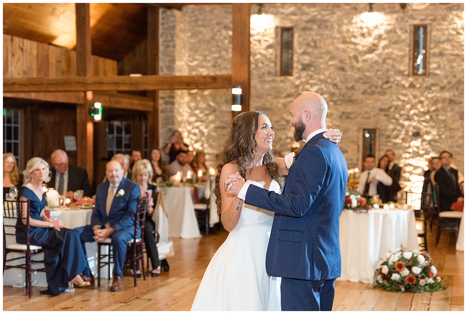 couple sharing their first dance inside stone barn as guests watch at the barn at silverstone