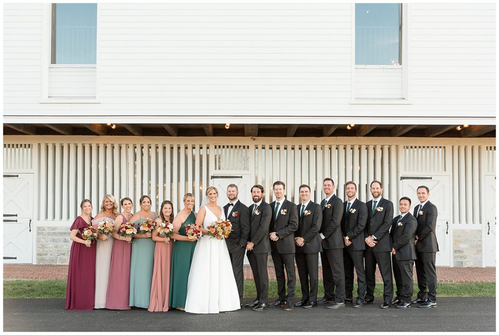 couple with their bridal party in front of white barn at the star barn venue in lancaster pennsylvania