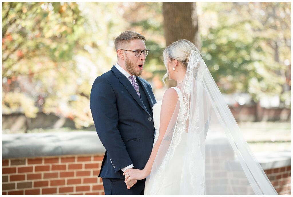 groom wowed as he sees his bride for the first time and they hold hands outdoors on fall day in philadelphia