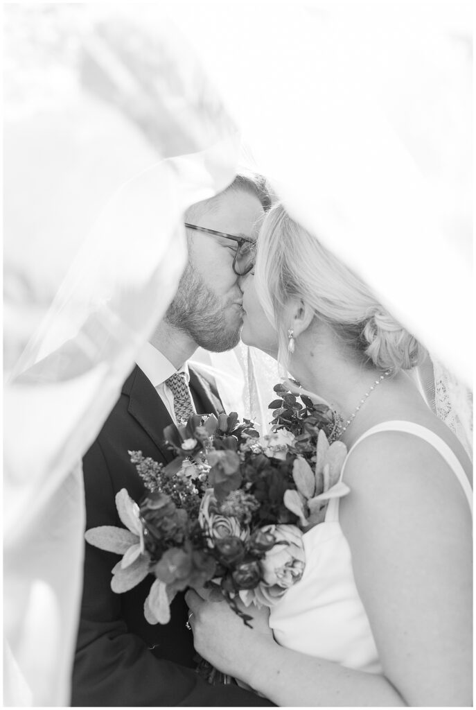 black and white photo of bride and groom kissing under long white veil in philadelphia pennsylvania