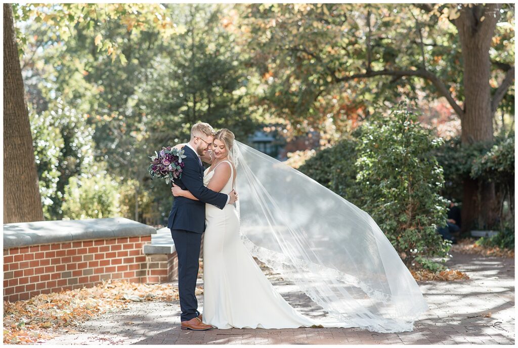 couple hugging as bride's long white veil blows in the breeze behind her at hotel monaco philadelphia