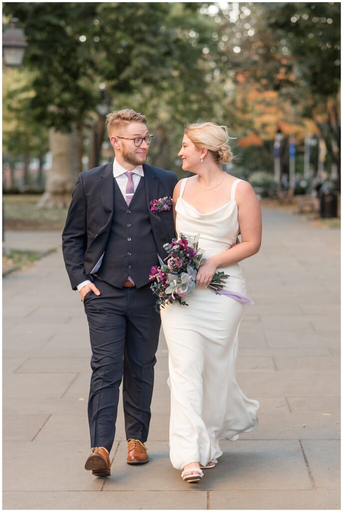 couple walking down city street towards camera as they look at each other in philadelphia